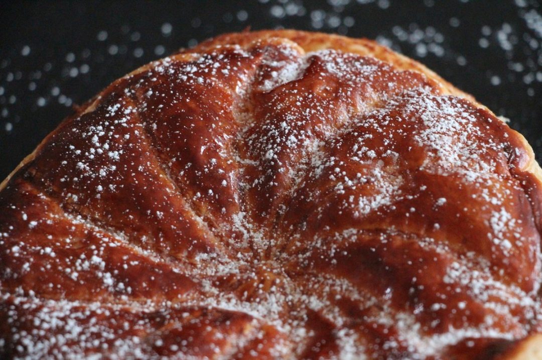 Surface dorée et croustillante de la galette des rois frangipane saupoudrée de sucre