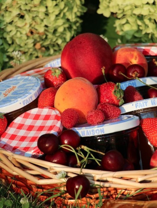Panier garni de fruits frais entourant des pots de recette confiture de grand-mère maison