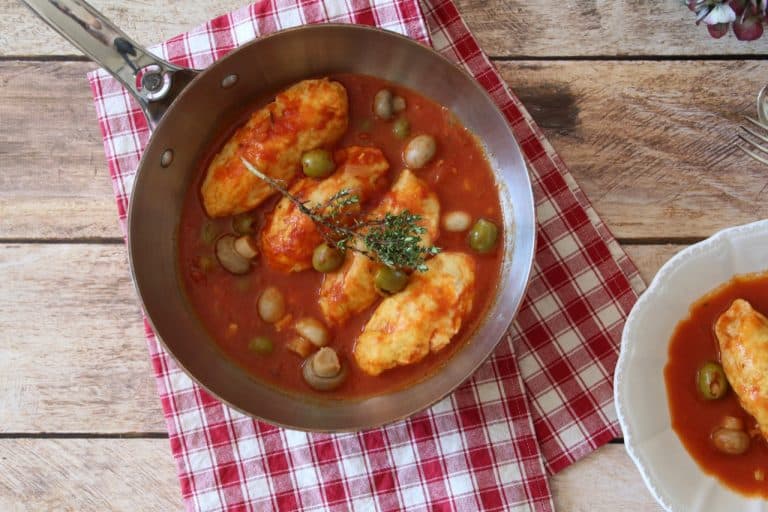 Quenelles de brochet dorées dans une sauce tomate, garnies d'olives et champignons