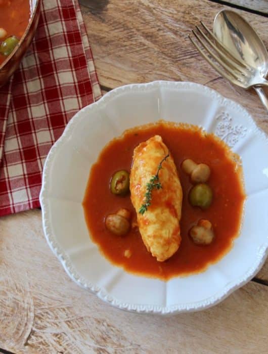 Quenelle de brochet nappée de sauce tomate, garnie de champignons et olives
