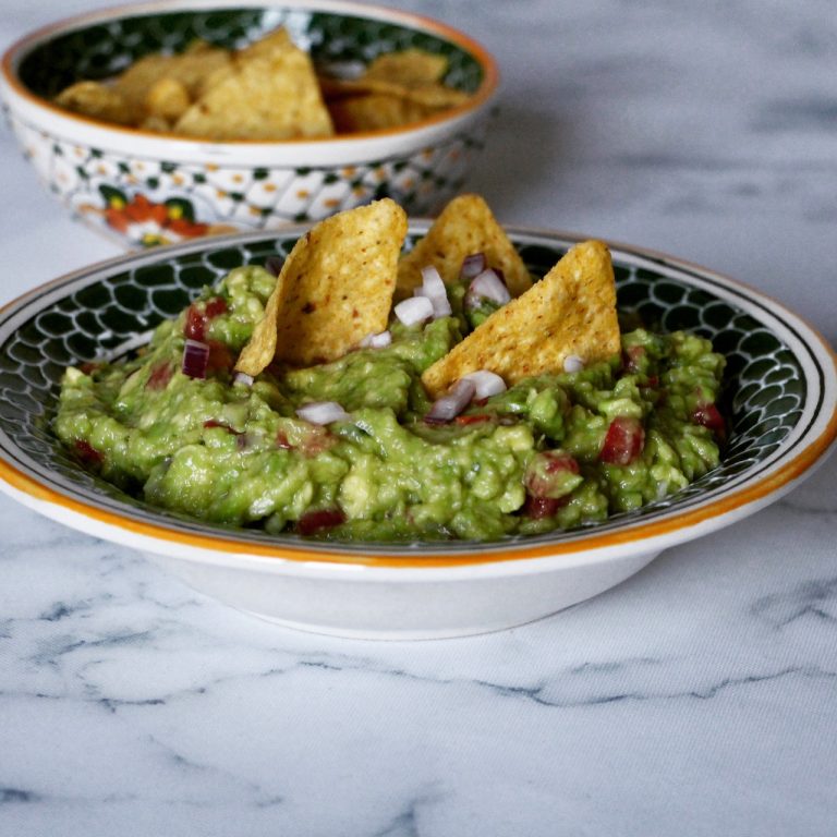 Guacamole crémeux avec dés de tomate et oignon, décoré de chips tortilla