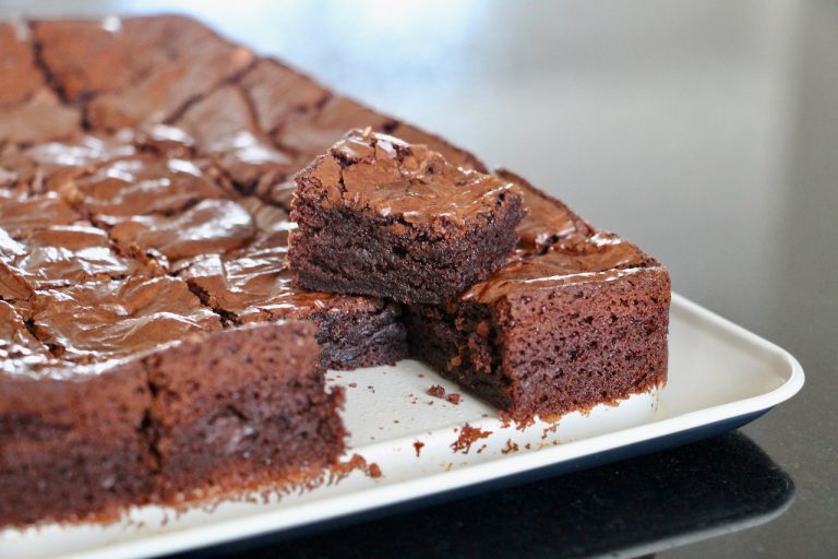 Brownie moelleux avec croûte brillante sur un plateau blanc, vue rapprochée