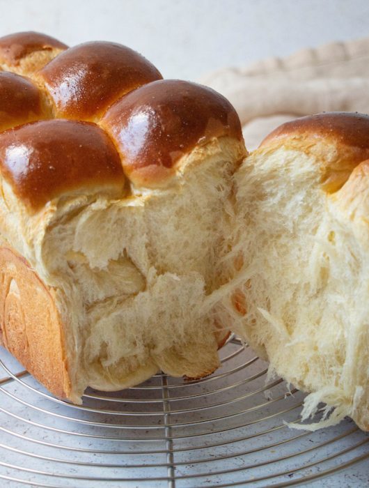Brioche nanterre dorée avec mie filante exposée sur grille métallique