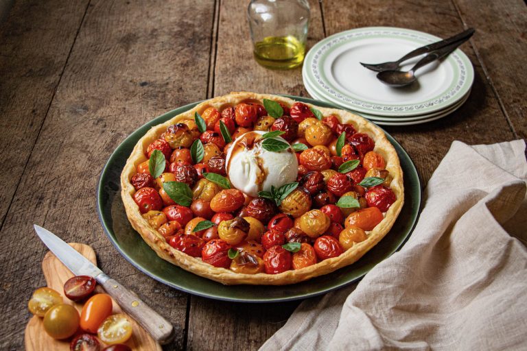 Tarte tomates cerises avec burrata crémeuse, décorée de feuilles de basilic frais