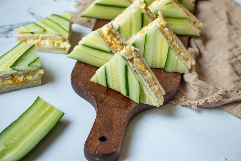Triangles de sandwich mimosa garnis de concombre sur planche en bois rustique