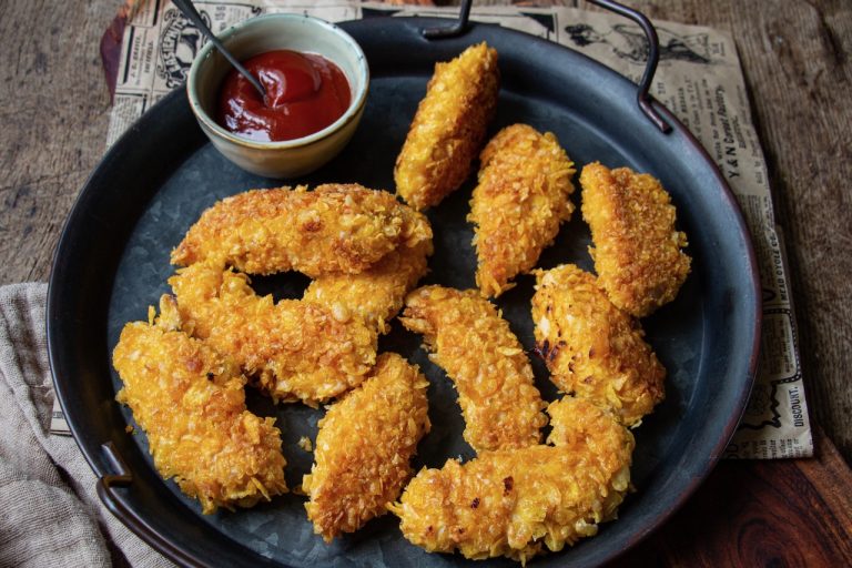 Tenders dorés et croustillants sur assiette noire, accompagnés de sauce ketchup