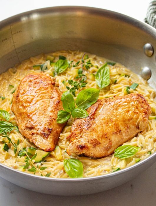Poulet doré sur orzo crémeux avec courgettes, herbes fraîches en garniture