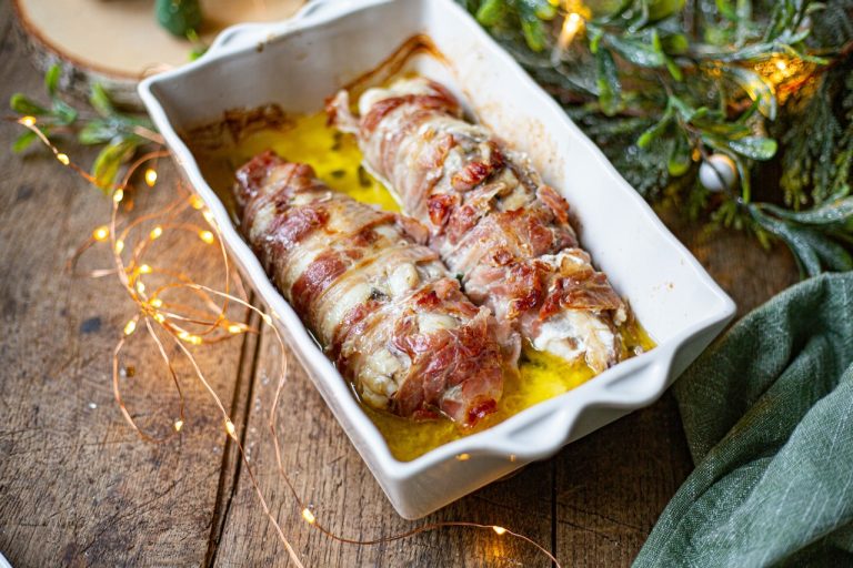 Rôti de lotte enrobé de lard, doré et juteux dans un plat blanc, ambiance festive