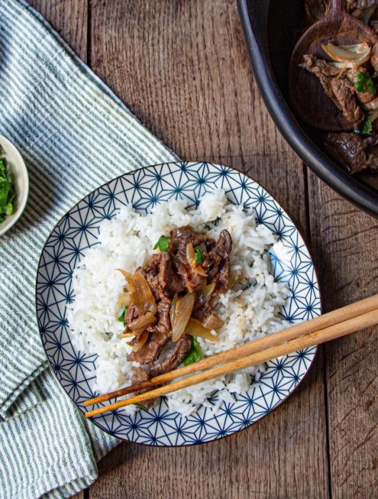 Assiette de boeuf aux oignons sur riz blanc, servie avec coriandre fraîche