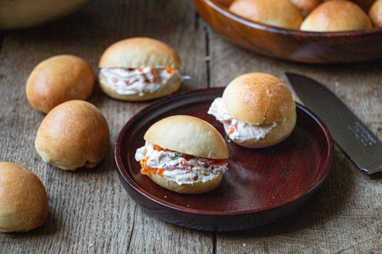 Pain navette garni de fromage crémeux et caviar sur assiette en bois rustique