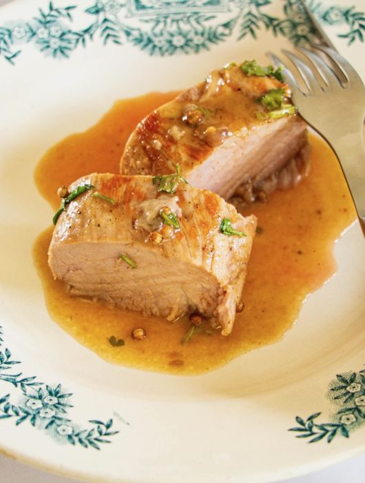 Filet mignon de porc nappé de sauce miel coriandre, servi sur assiette fleurie