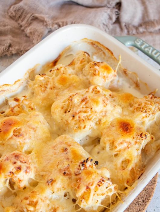 Gratin de chou-fleur doré, fromage fondu, dans un plat en céramique blanche