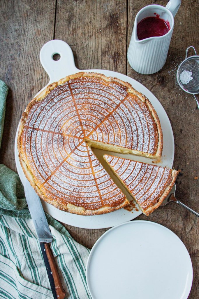 Tarte au fromage blanc saupoudrée de sucre glace, part découpée sur assiette blanche