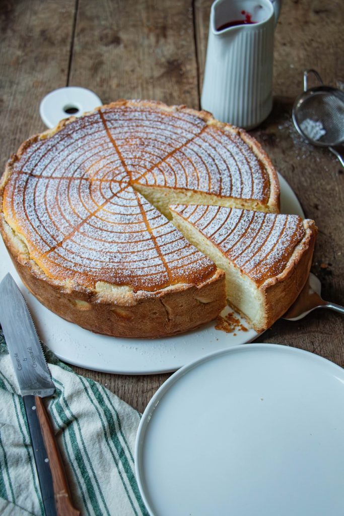Tarte au fromage blanc saupoudrée de sucre glace, tranche découpée délicatement