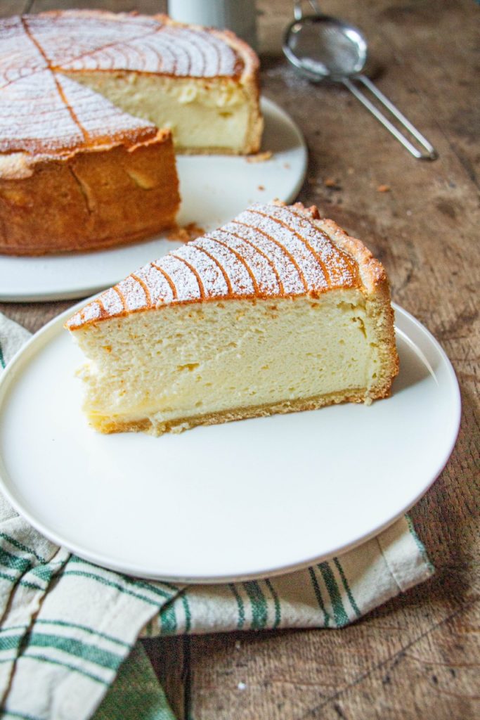 Tranche de tarte au fromage blanc poudrée de sucre sur assiette blanche