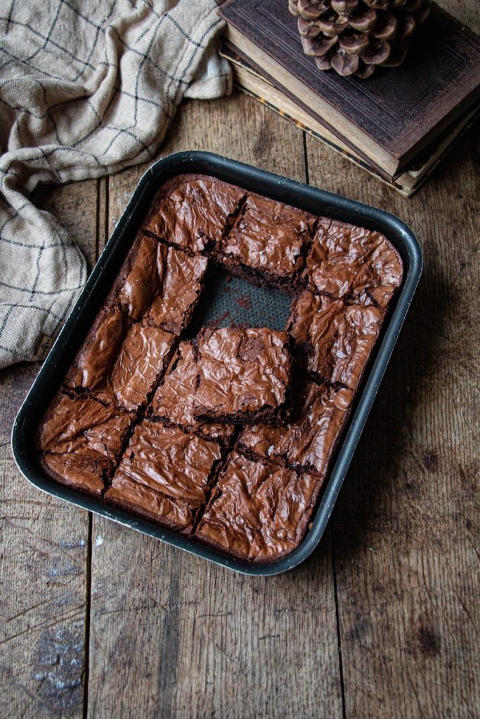 Brownie découpé en carrés, texture fondante, dans un moule sur table rustique