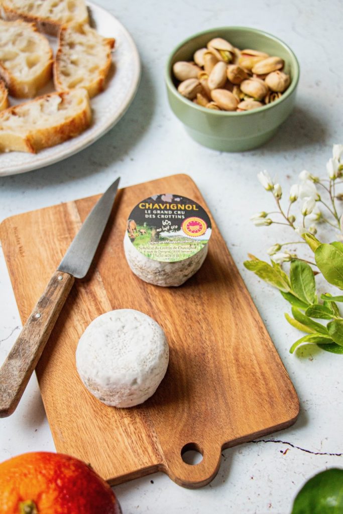 Crottin de Chavignol sur planche en bois, avec pistaches et pain tranché