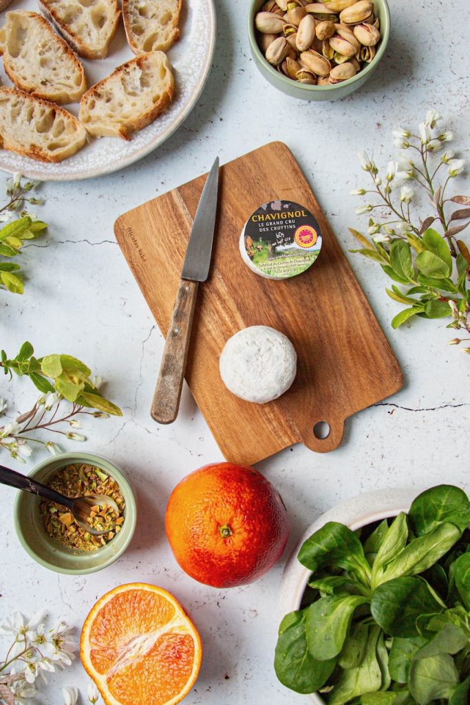 Tranches de pain, crottin de Chavignol, orange et pistaches sur planche en bois