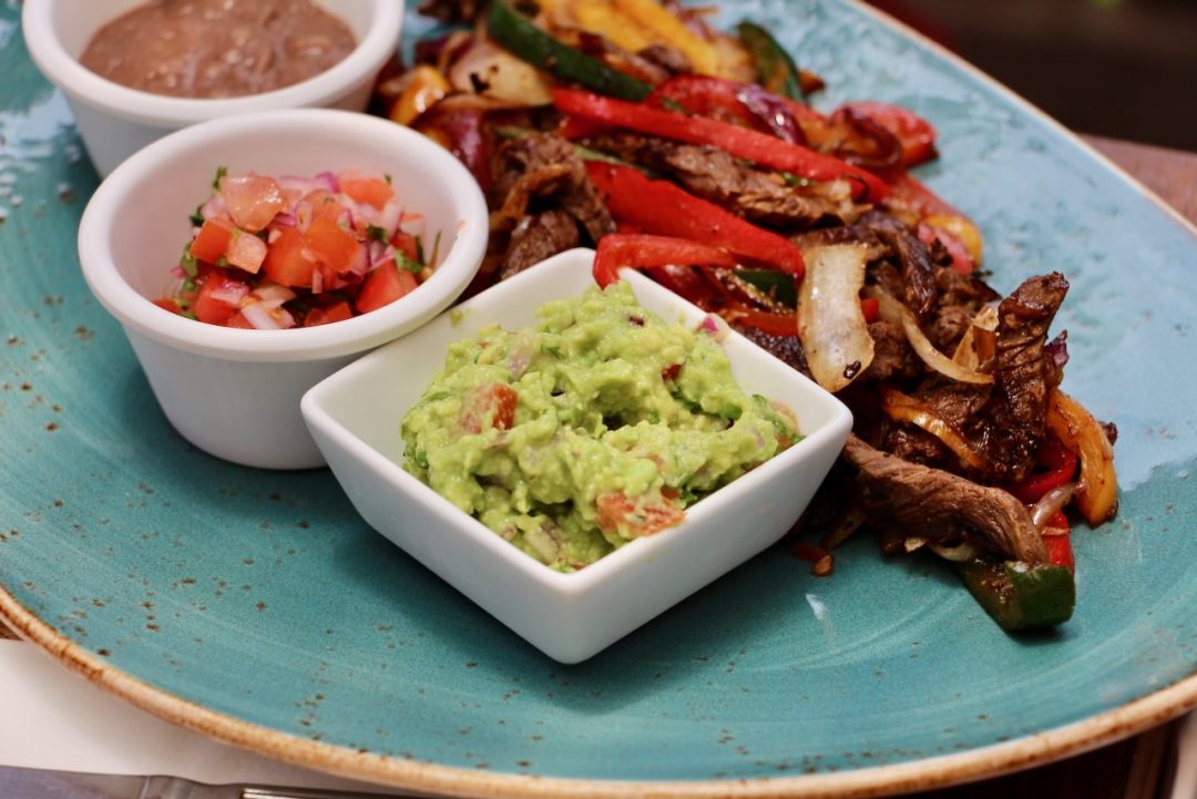Guacamole crémeux dans un bol blanc, entouré de légumes colorés, recette guacamole traditionnel