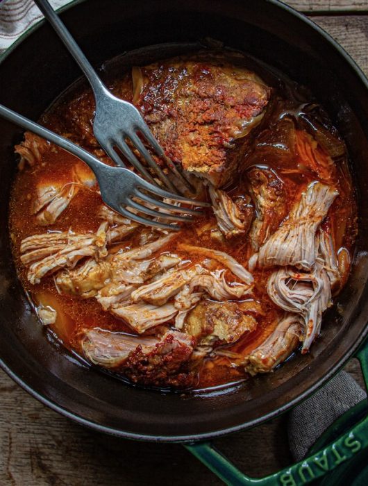 Effilochée de pulled pork juteux dans une cocotte en fonte, vue plongeante