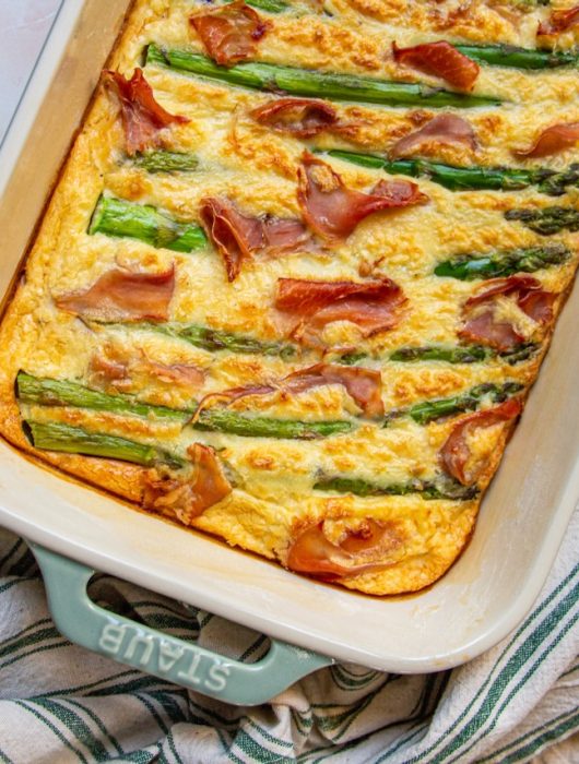 Quiche dorée avec asperges vertes et jambon cru dans un plat