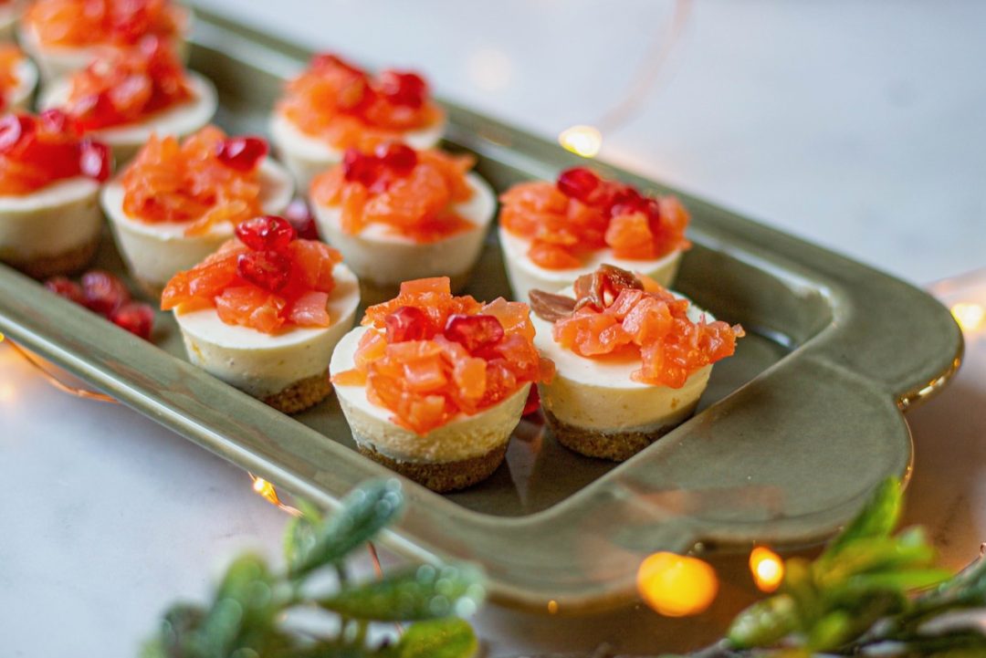 Mini cheesecakes salés garnis de saumon et grains de grenade sur plateau élégant