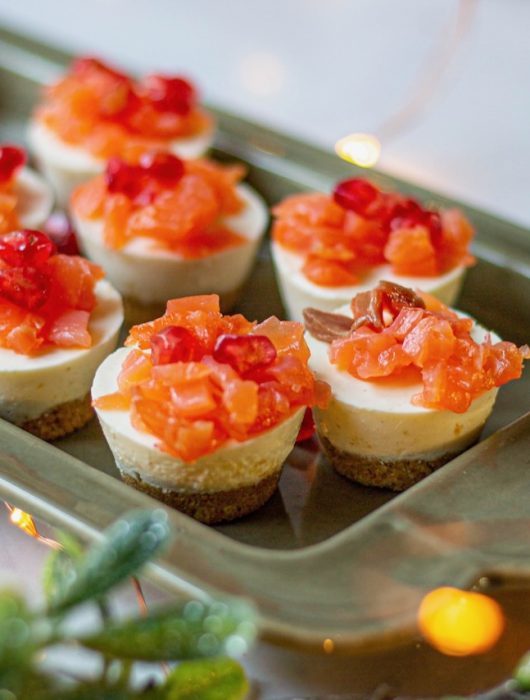 Mini cheesecakes salés garnis de saumon et grains de grenade sur plateau élégant