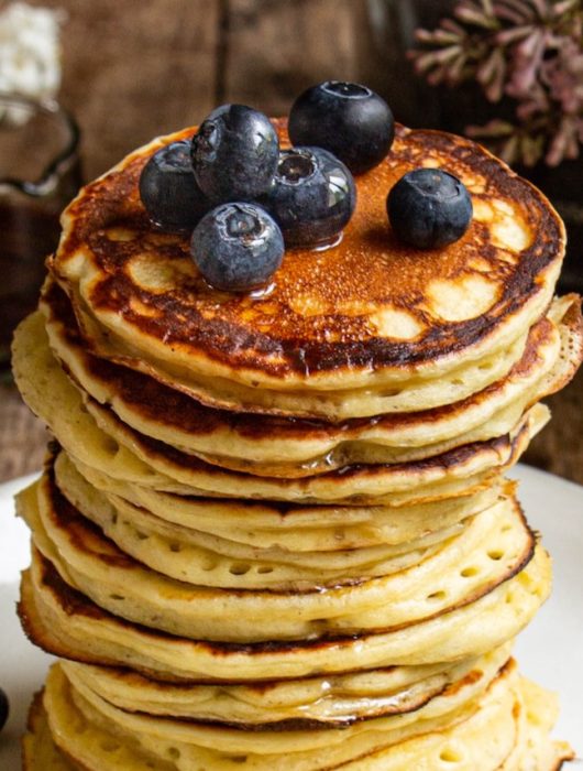 Empilement de pancakes yaourt dorés garnis de myrtilles fraîches et sirop