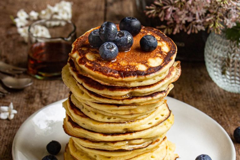 Empilement de pancakes yaourt dorés garnis de myrtilles fraîches et sirop