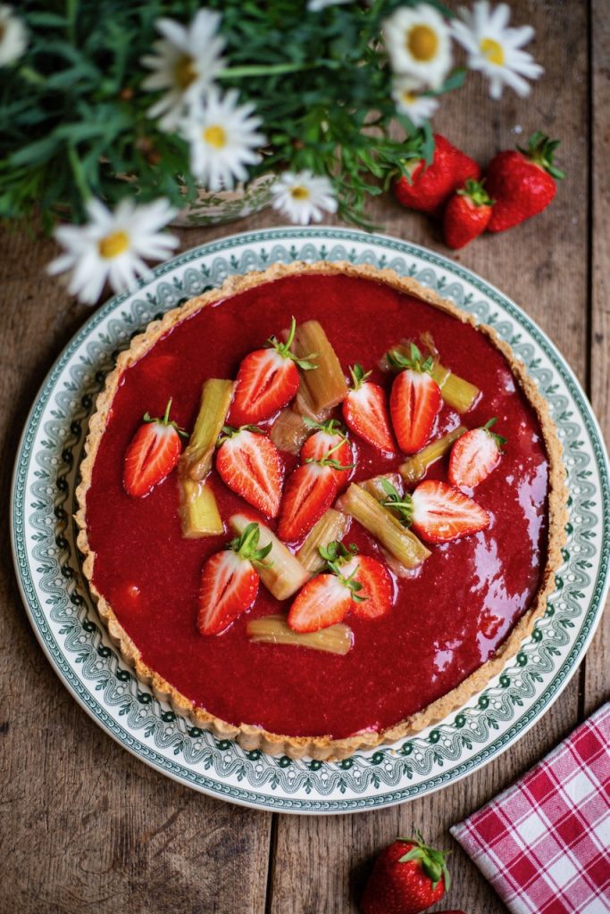 Tarte rhubarbe fraise avec fraises fraîches et morceaux de rhubarbe sur assiette décorative